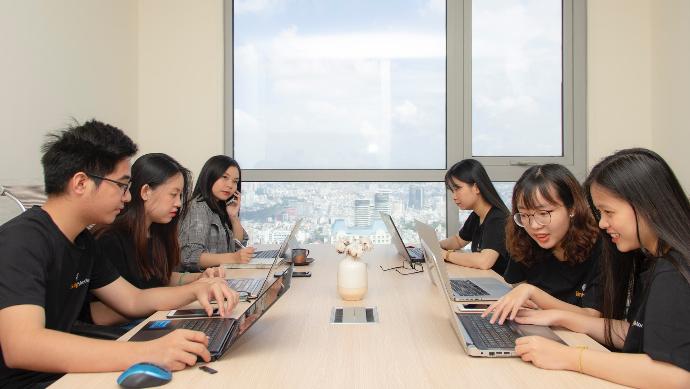 six people sitting at table using laptop computers